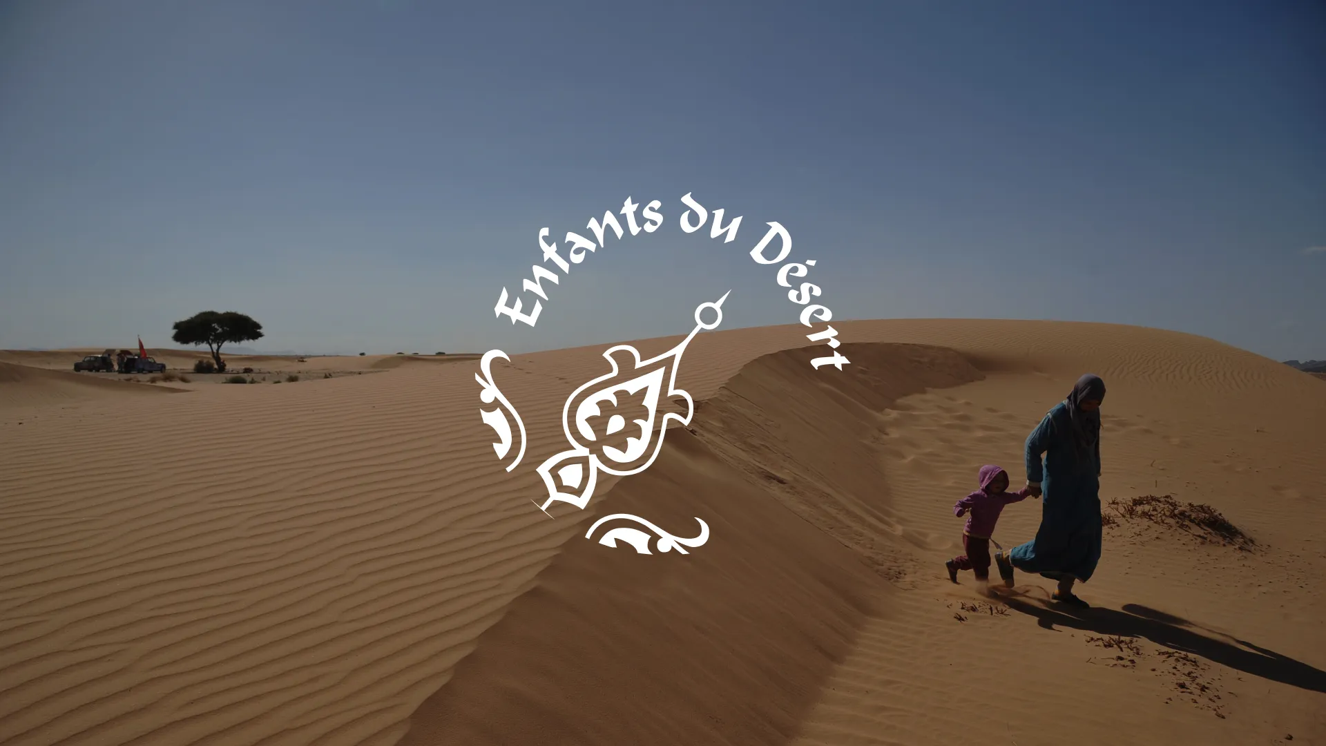 Logo Enfants du Désert appliqué sur une photo de dunes avec une scène familiale dans le désert.